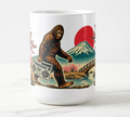 Coffee mug featuring vintage-style Bigfoot artwork with a boombox, pink cherry blossoms, Mount Fuji, and a red sun.